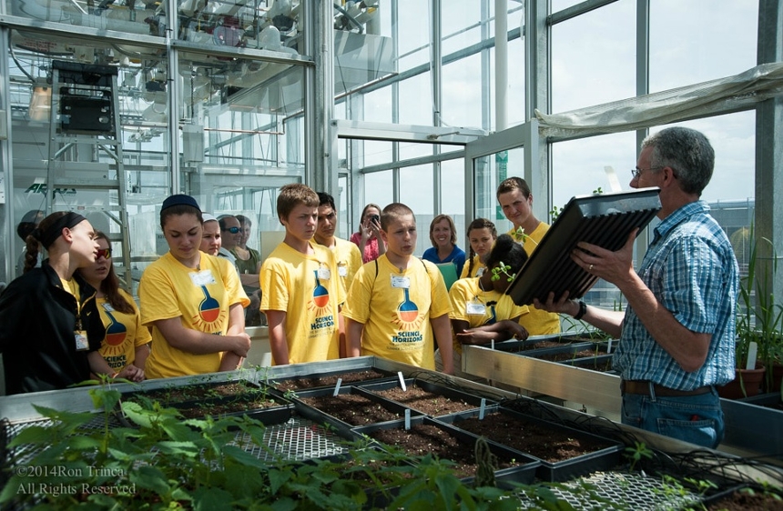 Dr. Althoff showing HS students a plant tray up in the greenhouse