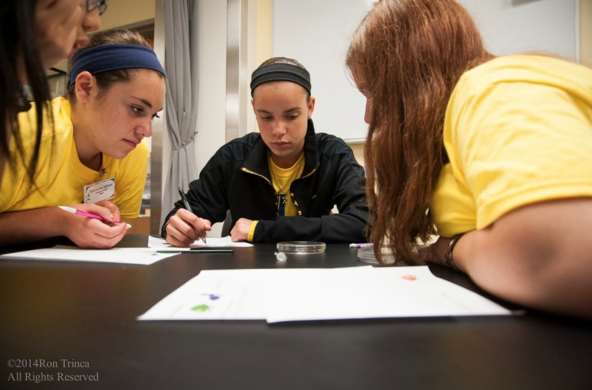 Four female HS students observing a sample and taking notes